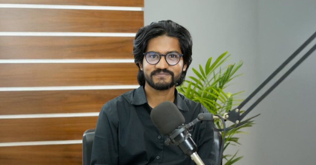 A confident South Asian man in a studio, ready for podcasting with a professional microphone setup.